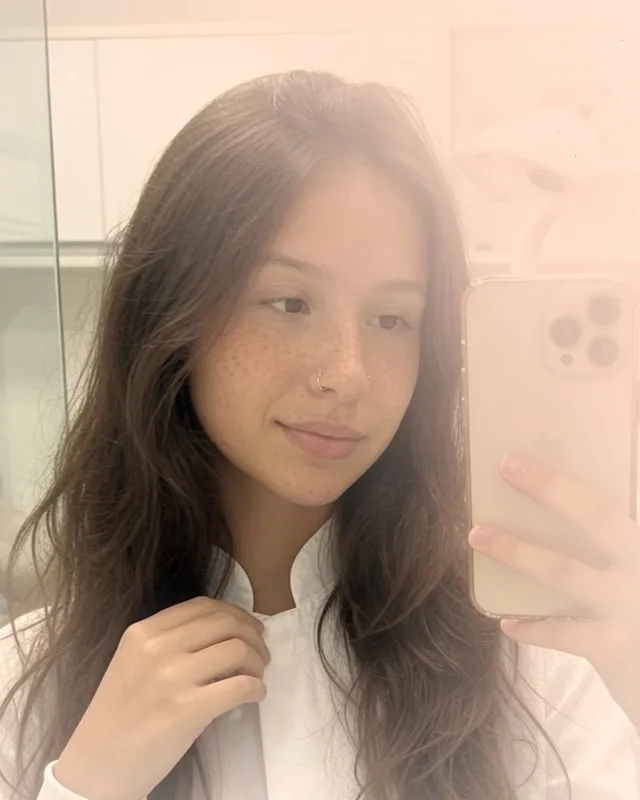 Mulher de cabelo castanho com sardas tirando uma selfie no espelho