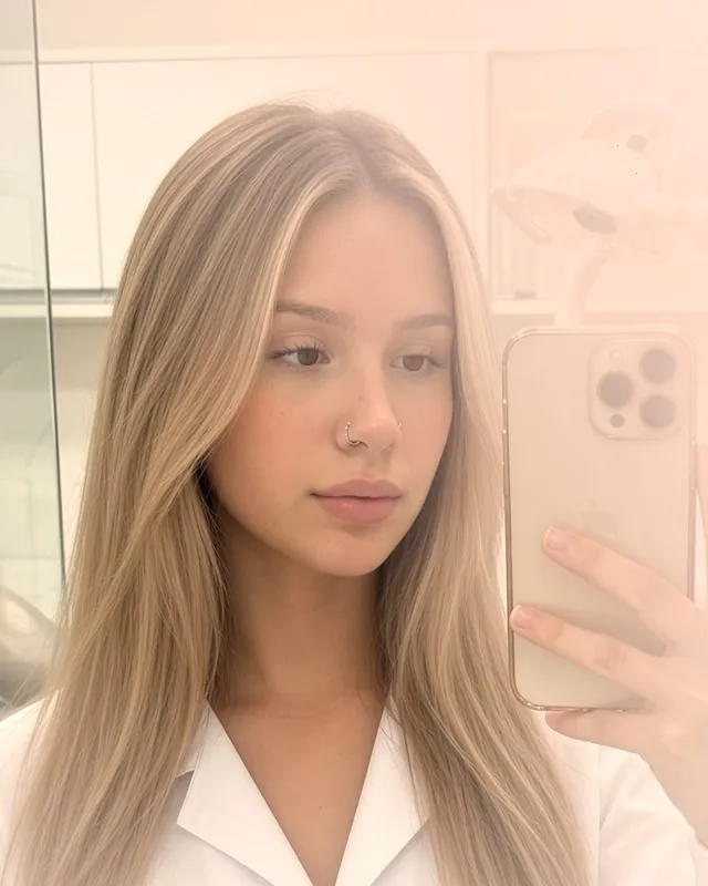 Mulher de cabelo loiro e liso tirando uma selfie no espelho